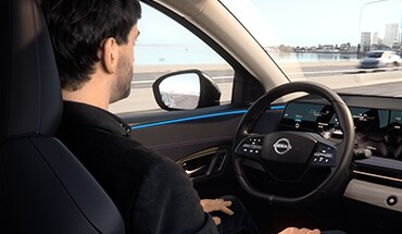 2023 Nissan Ariya person using hands-off driving to illustrate driver assist and safety technology features.