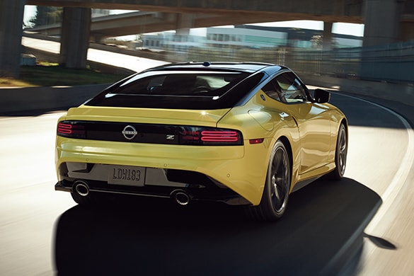 2023 Nissan Z in yellow driving on a highway with two-tone exterior.