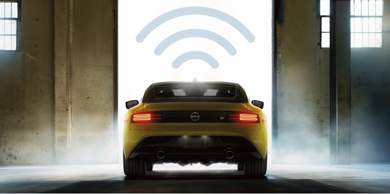 Rear view of a yellow 2024 Nissan Z driving out of a garage with a wifi connectivity symbol hanging above it