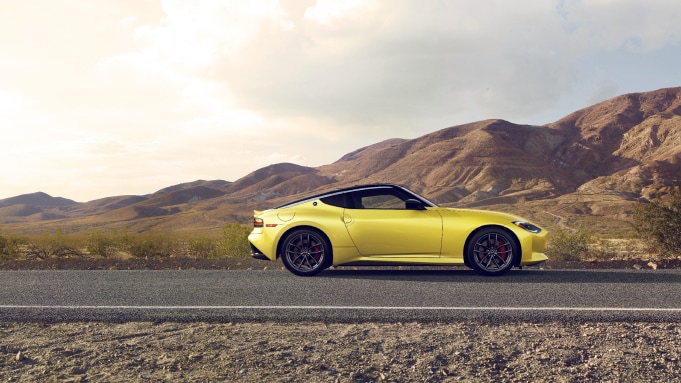 Side view of a yellow 2024 Nissan Z parked on a road surrounded by sandy hills