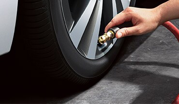 2023 Nissan Armada person airing tires to illustrate tire pressure monitoring system.