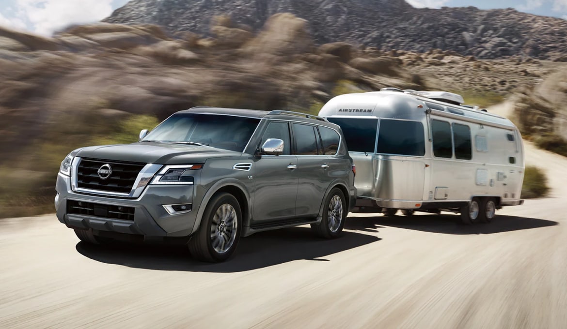 2024 Nissan Armada pulling a trailer on a dirt road