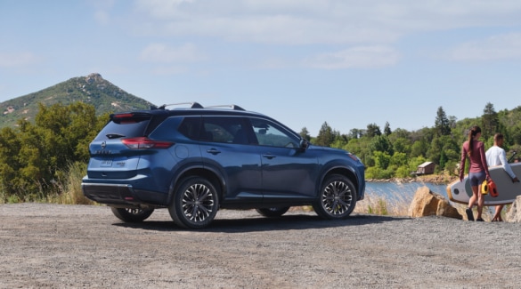 Blue Nissan Rogue driving across from mountains.
