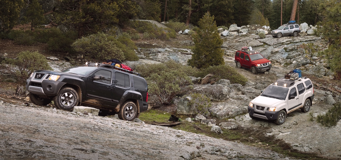 Four Nissan Xterras parked on rocks while carrying camping gear