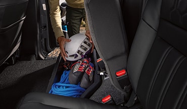2023 Nissan Frontier rear seat lifted to show under-seat storage of climbing rope and gear.
