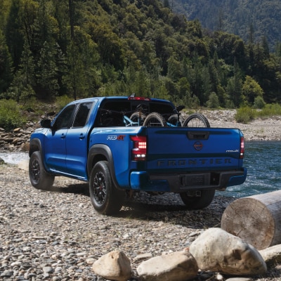 Blue 2024 Nissan Frontier pickup truck parked by river