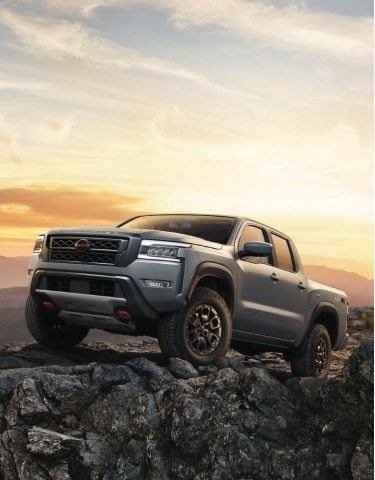 Grey 2024 Nissan Frontier parked on rocky outcropping at sunset