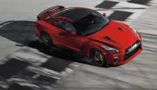2023 Nissan GT-R in Solid Red crossing checkered line on racetrack.