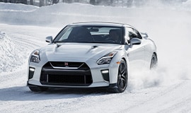 Nissan GT-R driving around a curve in the snow.