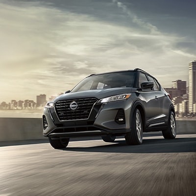 2024 Nissan Kicks in grey on highway with city in background