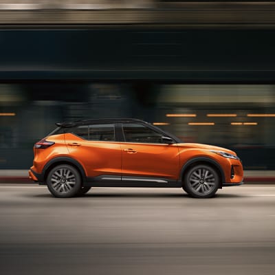 2024 Nissan Kicks in orange speeding down street highlighting fuel economy