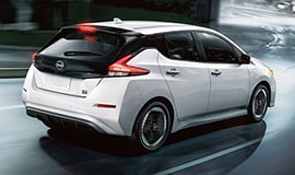 2023 Nissan LEAF in white on a wet city street at night