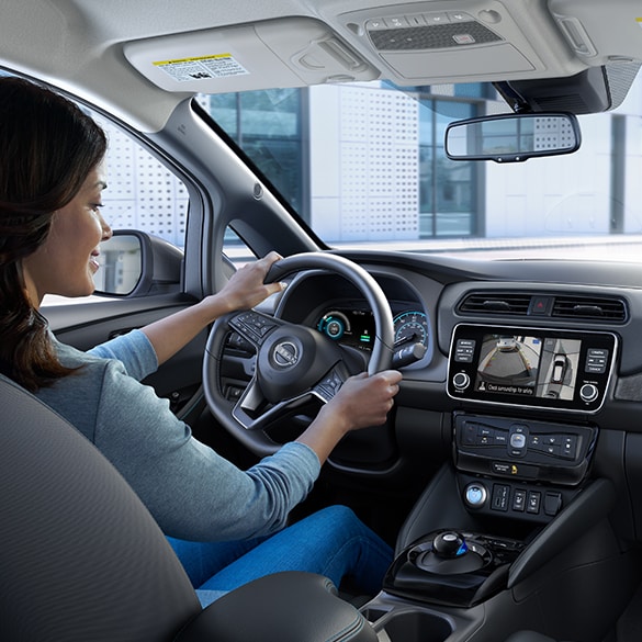 A woman driving 2025 Nissan LEAF and using its Intelligent Around View Monitor system