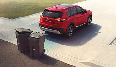 2023 Nissan Rogue showing car backing up and avoiding trash cans with rear sonar.