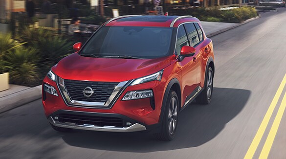 2023 Nissan Rogue in Scarlet Ember driving on a city street illustrating fuel economy.