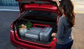 2023 Nissan Versa in Scarlet Ember Tintcoat with woman opening trunk