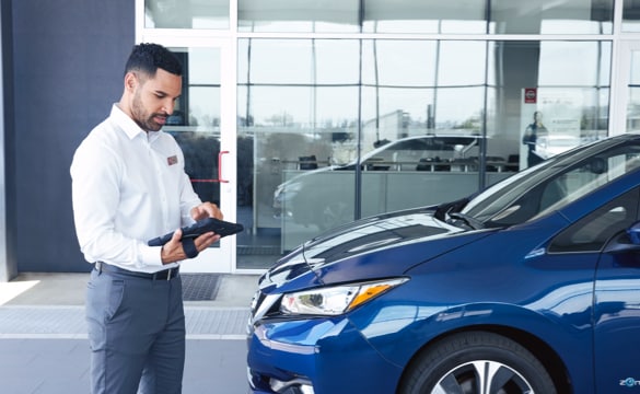 Nissan sales representative standing in front of a Nissan Vehicle