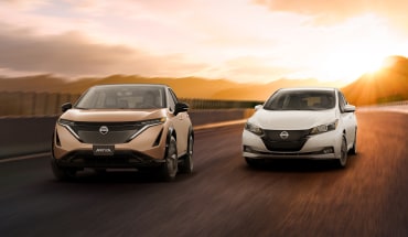 Nissan ARIYA and Nissan LEAF  driving side by side away from sunset