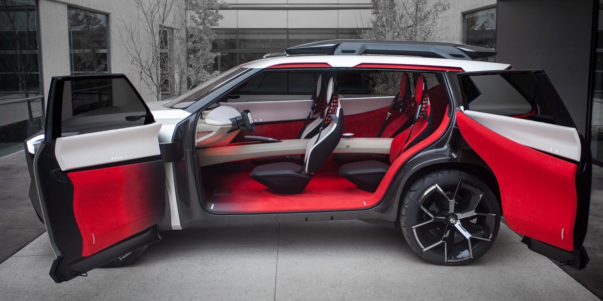Silver Nissan Xmotion autonomous intelligent concept SUV parked with its doors open showcasing its luxurious white and red interior