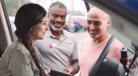 Happy customers test drive a Nissan Fleet vehicle at a Nissan dealership