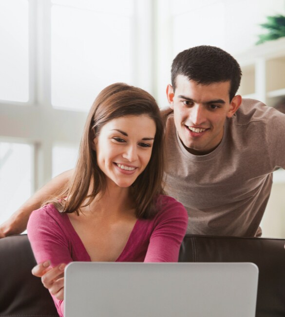 A man and woman on a laptop shopping for a new Nissan vehicle at home