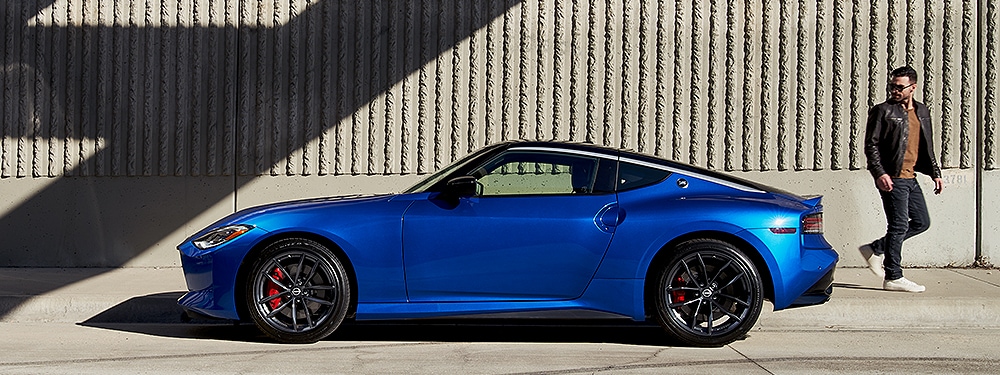 Side view of a blue 2024 Nissan Z parked in front of a textured wall