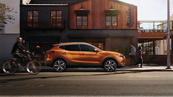 Side profile of an orange 2021 Nissan Qashqai parked on the side of the road